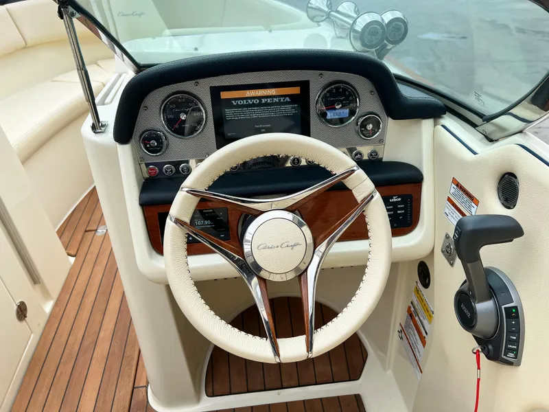 Slide: The Image of 2022 Chris-Craft Launch 27 dashboard with steering wheel and Volvo Penta controls. - 16
