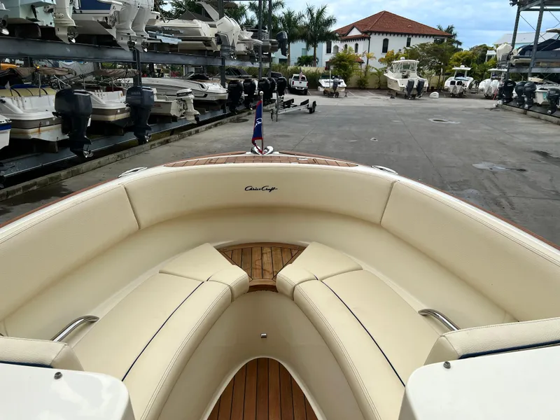 Slide: The Image of 2022 Chris-Craft Launch 27 boat with beige seating and wooden deck in a marina. - 19