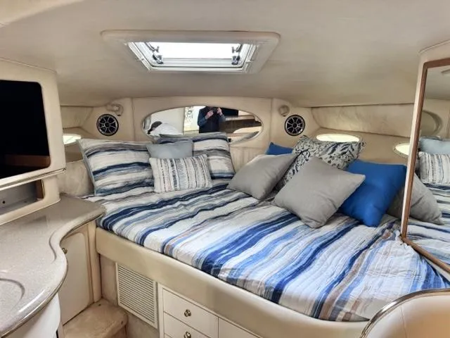 Slide: The Image of Interior cabin of 2000 Sea Ray 310 Sundancer with cozy bed and striped bedding. - 7