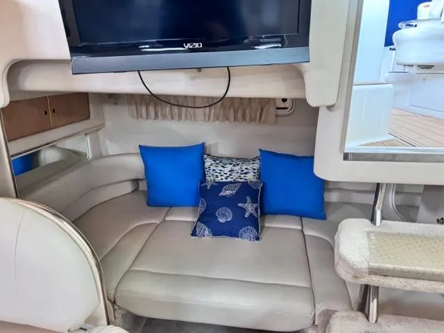 Slide: The Image of Interior of 2000 Sea Ray 310 Sundancer with TV, seating area, and blue cushions. - 8