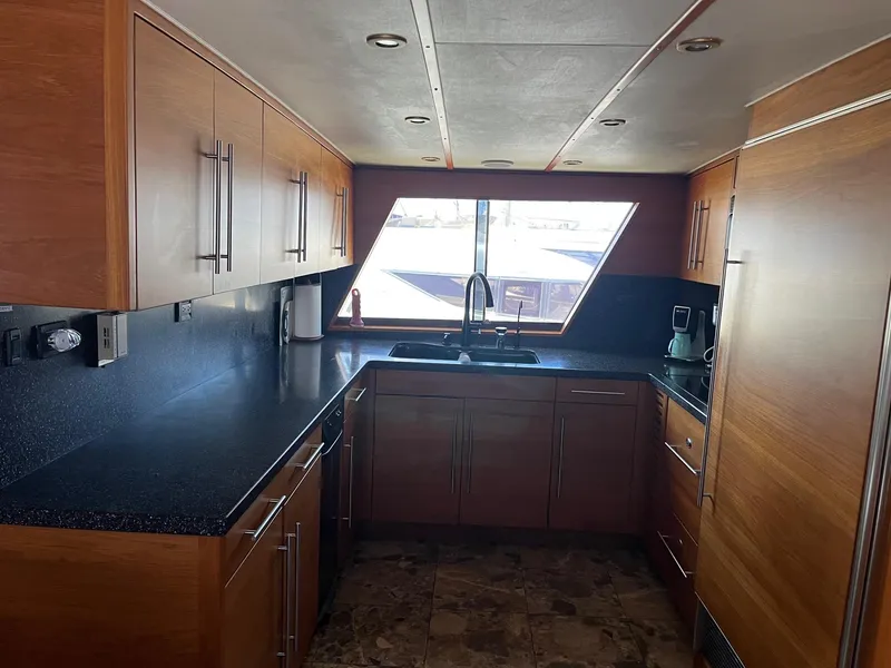 Slide: The Image of Modern kitchen in 1986 Hatteras 70' Cockpit Motor Yacht with wood cabinets and black countertops. - 13