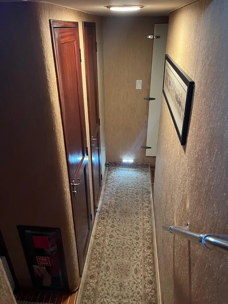 Slide: The Image of Hallway inside a 1986 Hatteras 70' Cockpit Motor Yacht with carpet and wooden doors. - 24