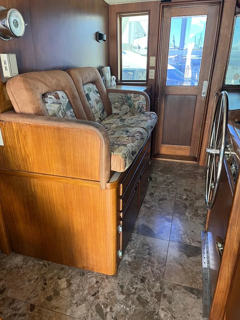 Slide: The Image of Interior of 1986 Hatteras 70' Cockpit Motor Yacht with wooden furnishings and cushioned seating. - 27