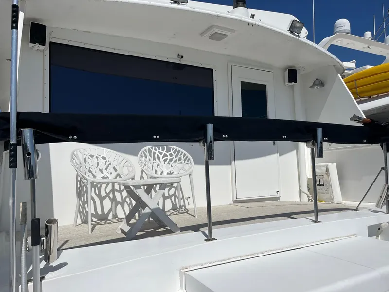 Slide: The Image of 1986 Hatteras 70' Cockpit Motor Yacht deck with white chairs and table. - 35