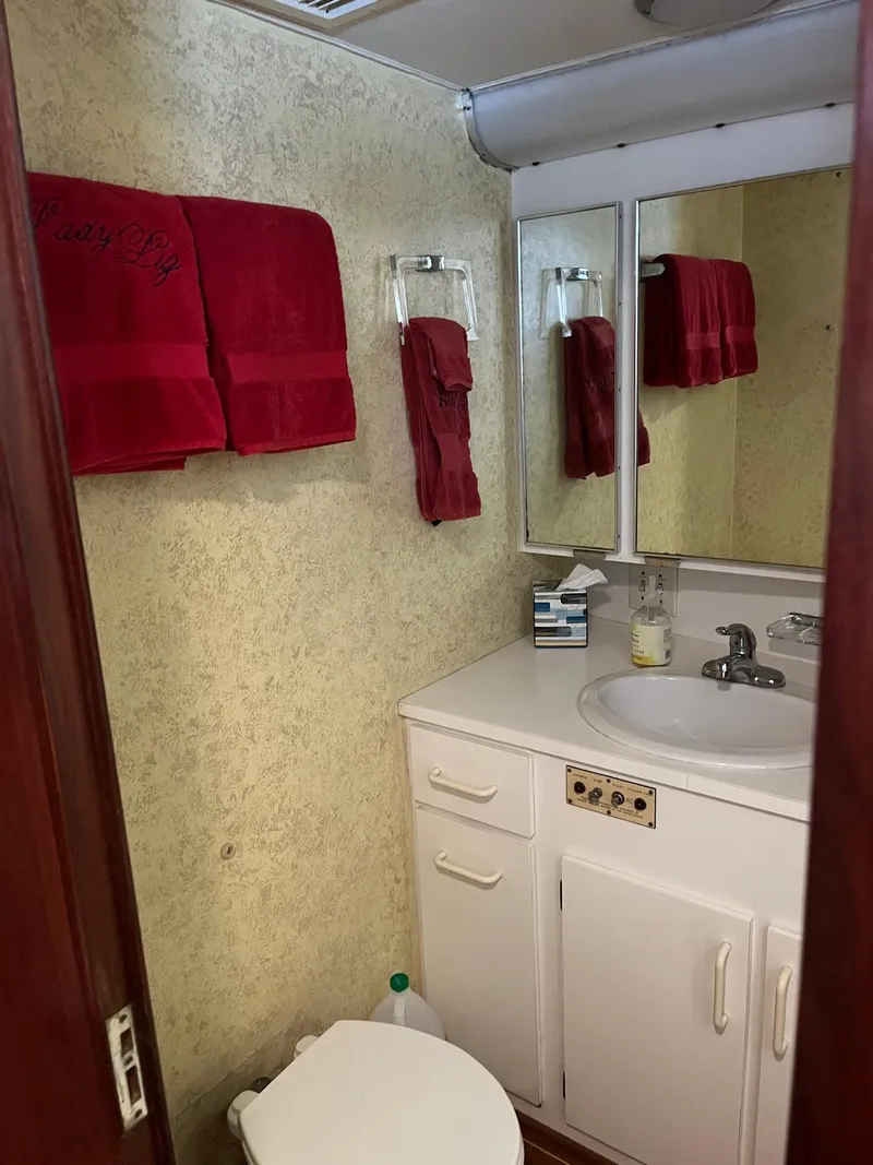 Slide: The Image of Bathroom in 1986 Hatteras 70' Cockpit Motor Yacht with red towels and white cabinetry. - 45