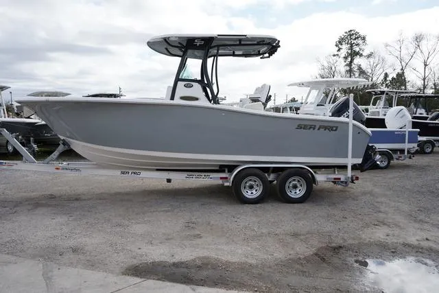 Slide: The Image of 2024 Sea Pro 242 DLX boat on a trailer in a marina. - 1