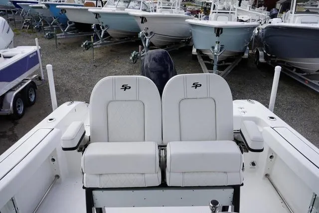 Slide: The Image of 2024 Sea Pro 242 DLX boat with dual white seats, docked among other boats. - 14