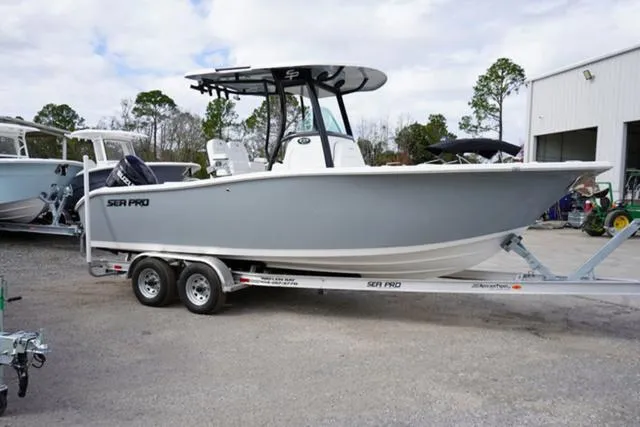 Slide: The Image of 2024 Sea Pro 242 DLX boat on a trailer, parked outdoors near a building. - 24