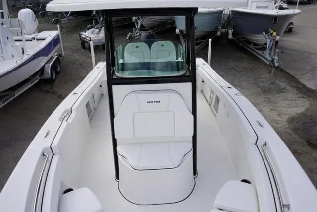 Slide: The Image of 2024 Sea Pro 242 DLX boat interior with seating and console, docked among other boats. - 27