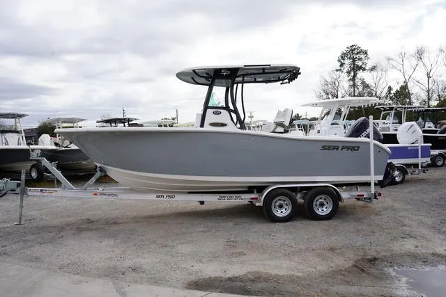 Slide: The Image of 2024 Sea Pro 242 DLX boat on a trailer in a marina. - 6