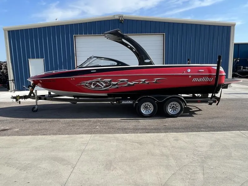 Slide: The Image of 2006 Malibu 23 LSV red boat on trailer in front of blue building. - 0