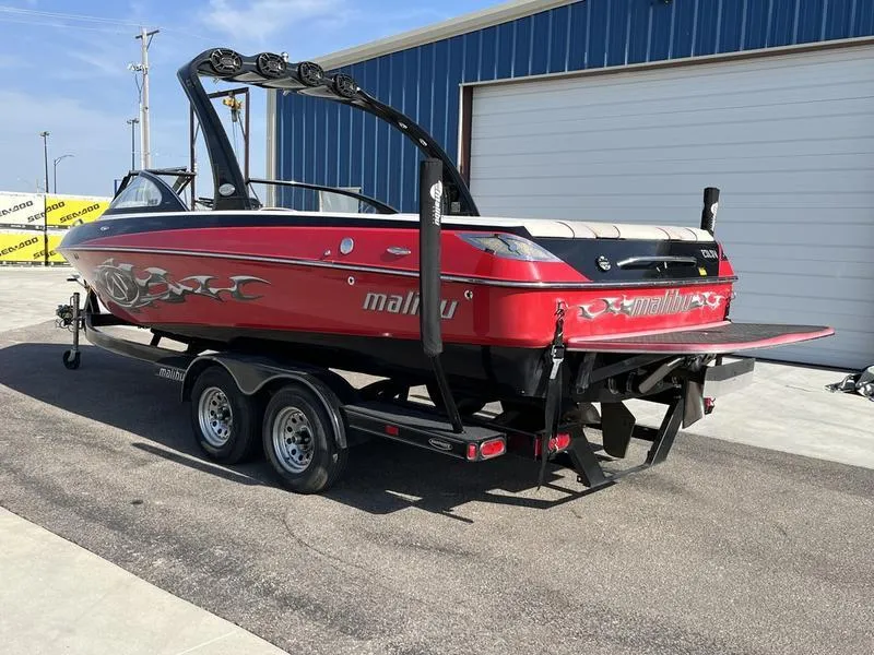 Slide: The Image of 2006 Malibu 23 LSV red wakeboard boat on trailer outside blue building. - 3