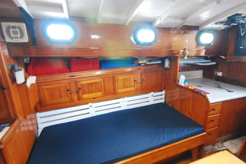 Slide: The Image of Interior of 1939 Concordia Motorsailer with wooden cabinetry and blue cushioned seating. - 10