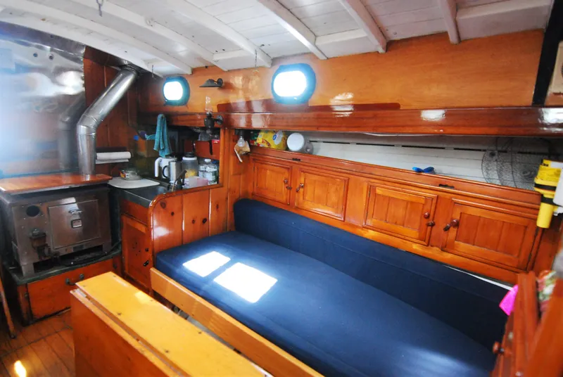 Slide: The Image of Interior of 1939 Concordia Motorsailer with wooden cabinetry and blue cushioned seating. - 15