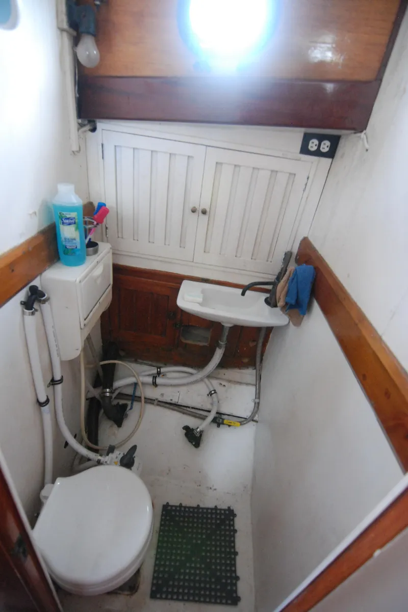 Slide: The Image of 1939 Concordia Motorsailer bathroom with compact toilet, sink, and wooden cabinetry. - 21