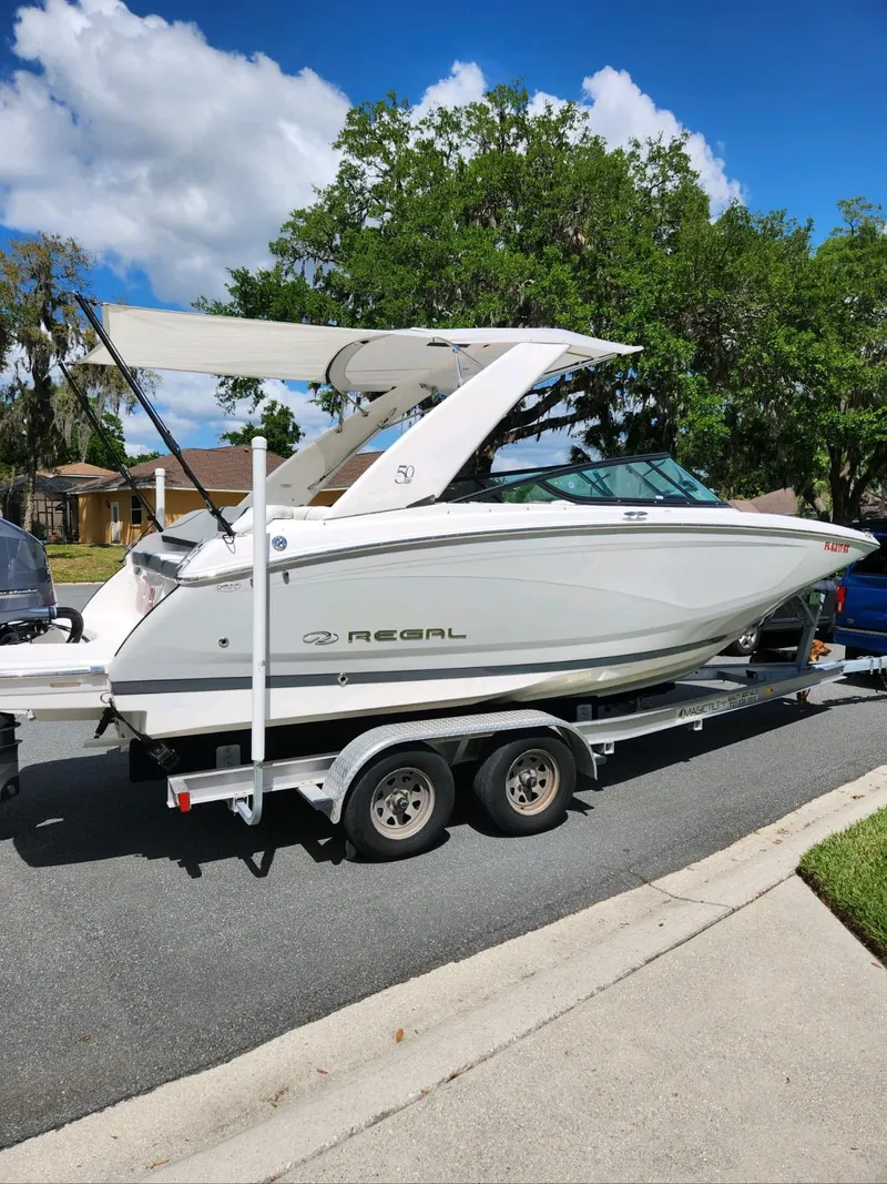 Slide: The Image of 2021 Regal 23 OBX boat on a trailer, parked on a residential street. - 11
