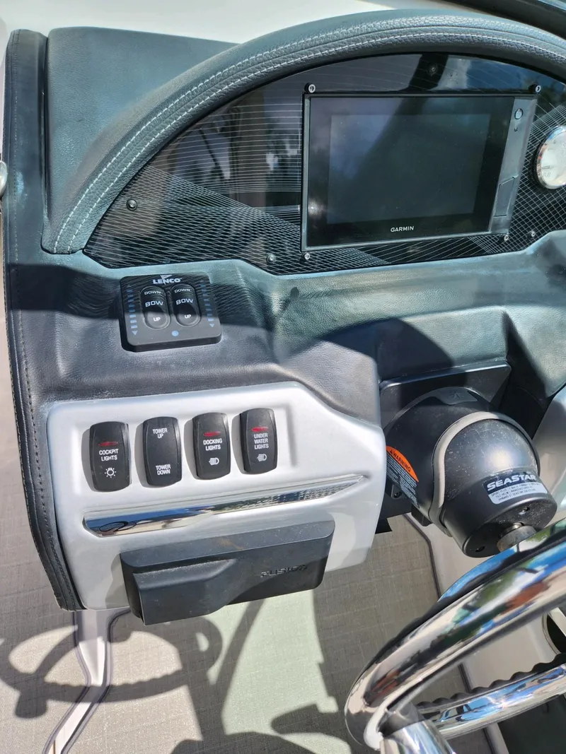 Slide: The Image of 2021 Regal 23 OBX boat dashboard with control switches and steering wheel. - 2