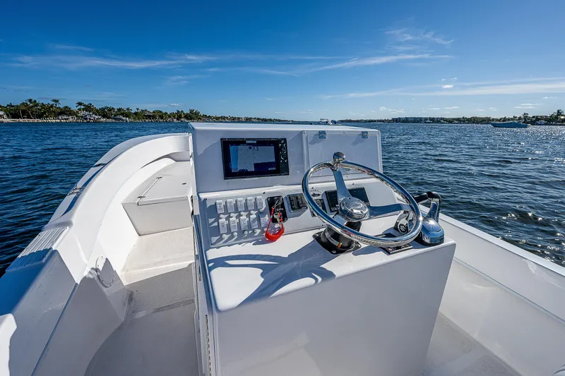 Slide: The Image of 2023 Dusky 27cc boat console with steering wheel and controls on open water. - 13