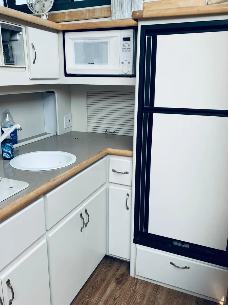 Slide: The Image of 1994 Carver 430 Cockpit Motor Yacht kitchen with microwave, sink, and refrigerator. - 12