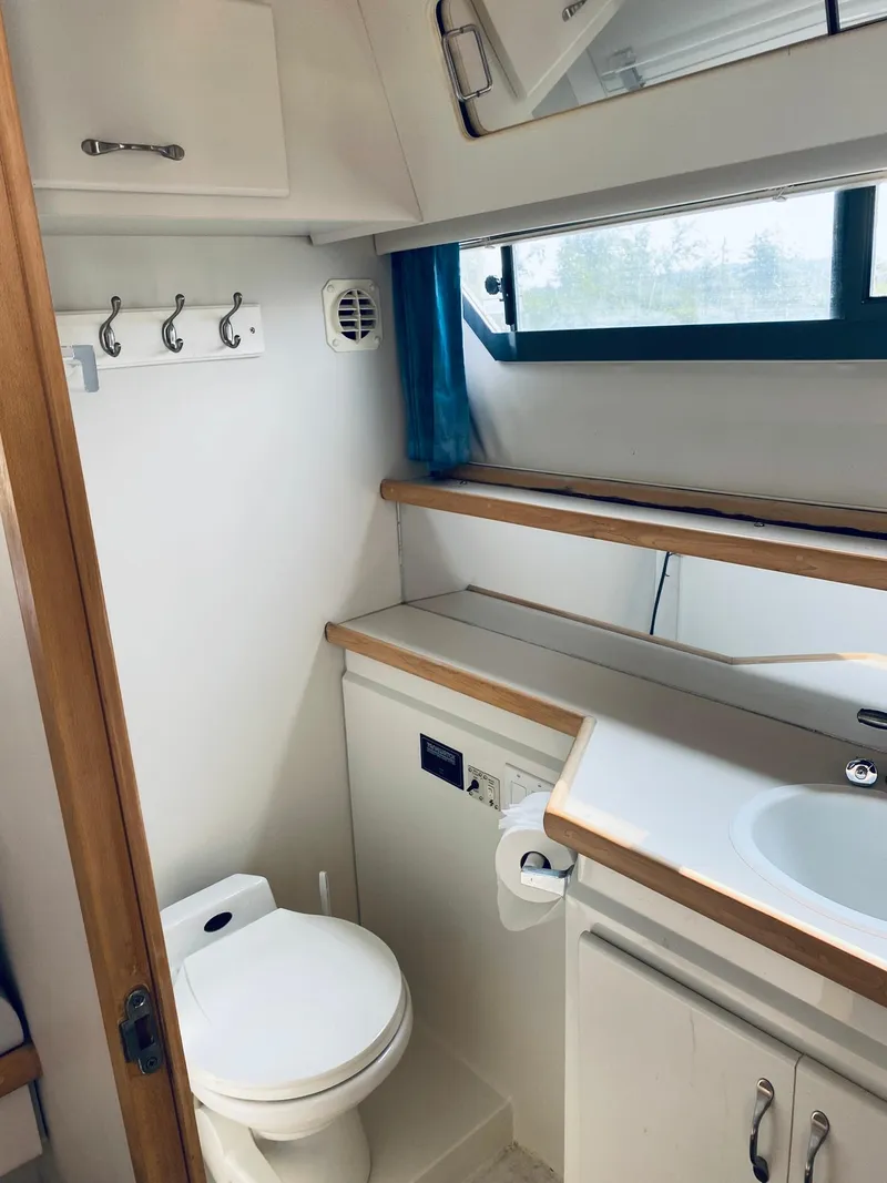 Slide: The Image of 1994 Carver 430 Cockpit Motor Yacht bathroom with toilet, sink, and storage cabinets. - 17