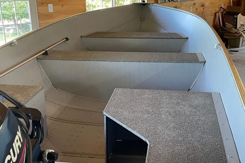 Slide: The Image of 2024 Lund WC 14 Tiller boat interior with carpeted seating and Mercury motor. - 3