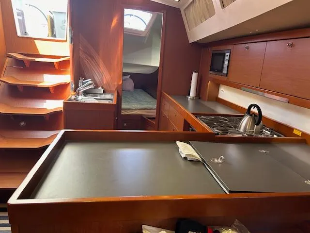 Slide: The Image of Interior of 2013 Beneteau 48 sailboat with wooden stairs and cozy seating area. - 13