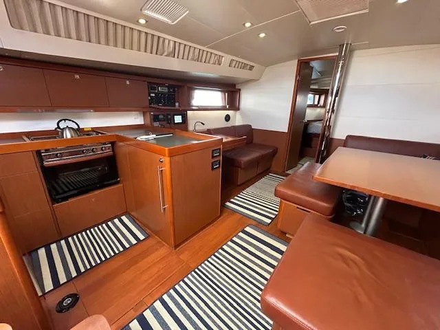Slide: The Image of Interior of 2013 Beneteau 48 sailboat with leather seating and wooden table. - 14