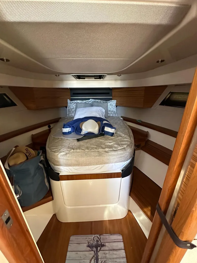 Slide: The Image of 2021 Boston Whaler 405 Conquest cabin interior with bed and wooden accents. - 7