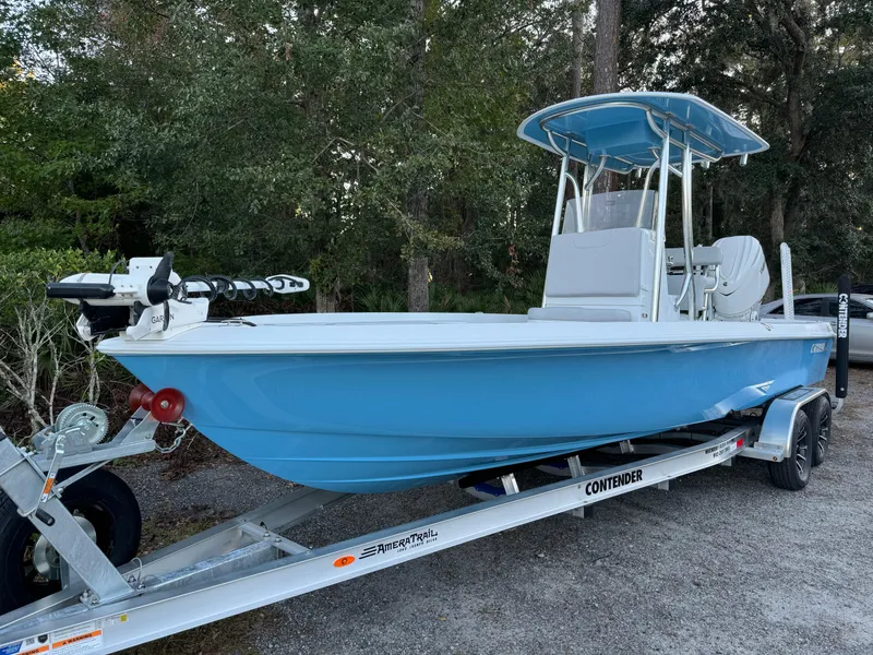 The Image of 2024 Contender 23 Bay boat on trailer, light blue hull, parked outdoors. - 1