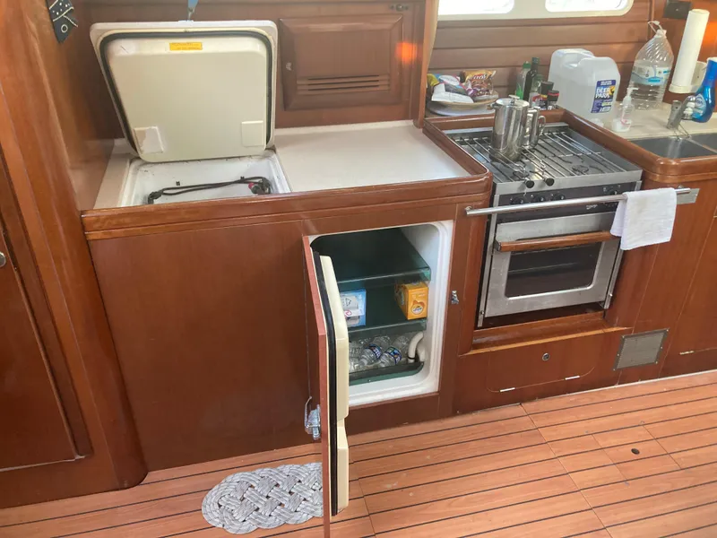Slide: The Image of Galley kitchen in 2005 Beneteau Oceanis 473 sailboat with stove, fridge, and storage. - 12