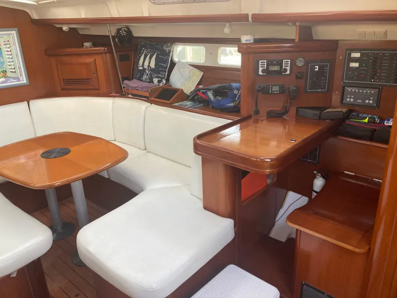 Slide: The Image of Interior of 2005 Beneteau Oceanis 473 sailboat with white seating and wooden table. - 13