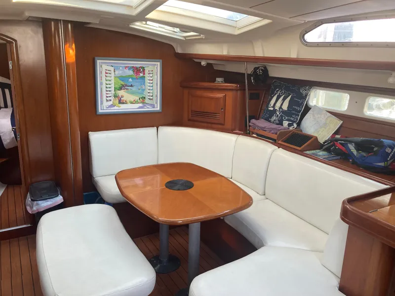 Slide: The Image of Interior of 2005 Beneteau Oceanis 473 sailboat with white seating and wooden table. - 8