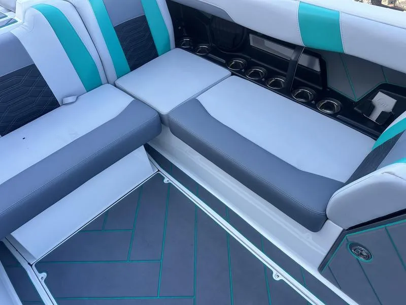 Slide: The Image of 2023 Malibu 26 LSV boat interior with gray and teal seating and cup holders. - 12