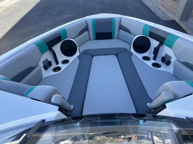 Slide: The Image of 2023 Malibu 26 LSV boat interior with gray and teal seating, cup holders, and speakers. - 15