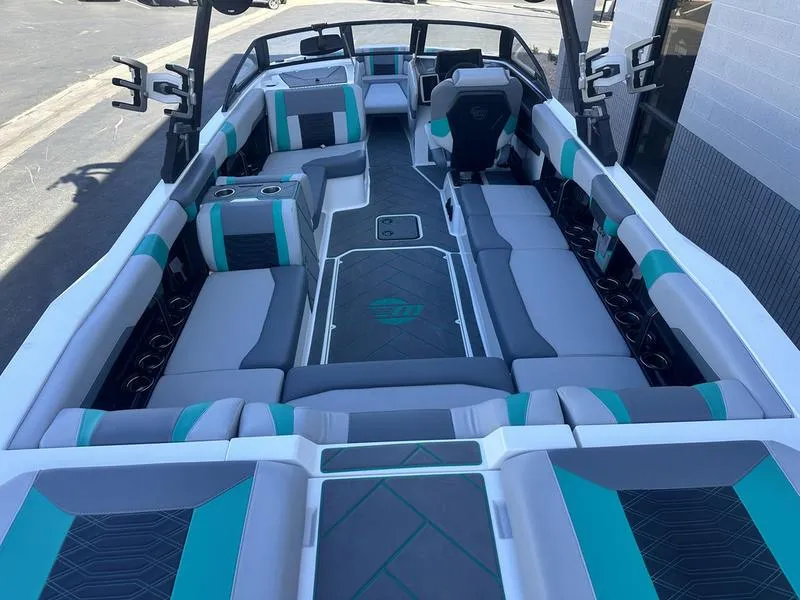 Slide: The Image of 2023 Malibu 26 LSV boat interior with teal and gray seating, spacious layout. - 9