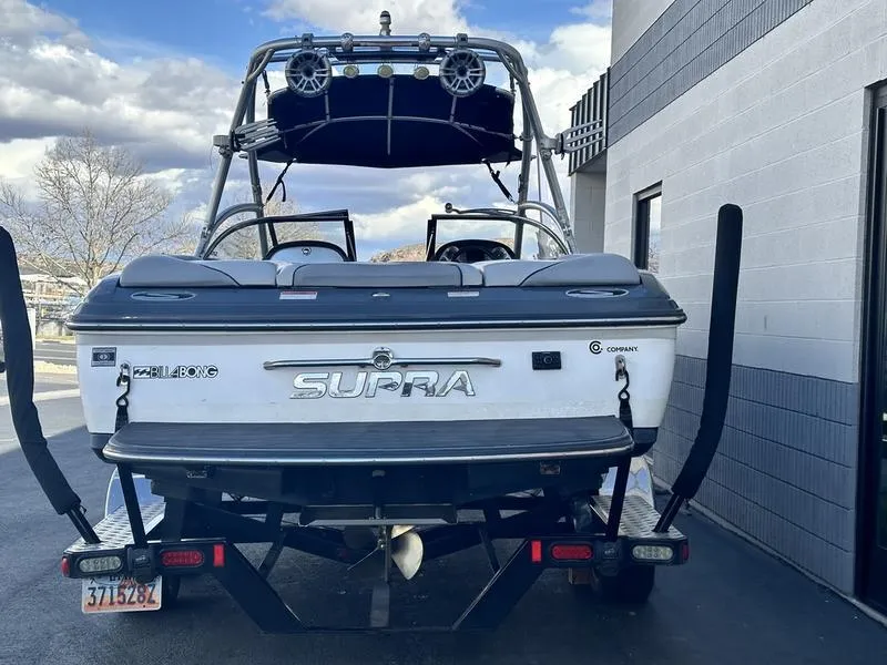 Slide: The Image of 2010 Supra Launch 24V Worlds Edition boat, rear view, parked near a building. - 3