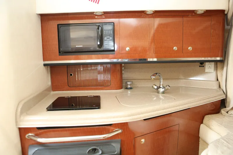 Slide: The Image of 2004 Sea Ray 290 Amberjack galley with microwave, sink, and stove. - 24