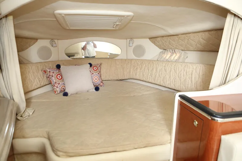 Slide: The Image of 2004 Sea Ray 290 Amberjack cabin interior with beige bedding and decorative pillows. - 28