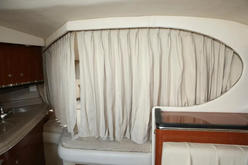 Slide: The Image of 2004 Sea Ray 290 Amberjack cabin interior with curtains and kitchenette. - 32
