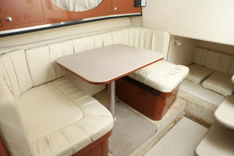 Slide: The Image of 2004 Sea Ray 290 Amberjack cabin interior with beige seating and dining table. - 33