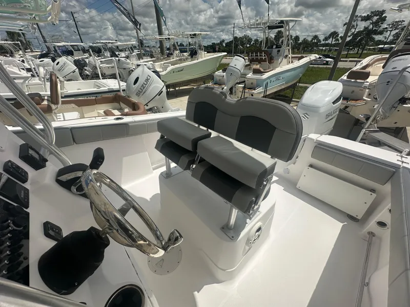 Slide: The Image of 2022 Aquasport 2300 boat interior with dual seats and steering wheel, surrounded by other boats. - 12