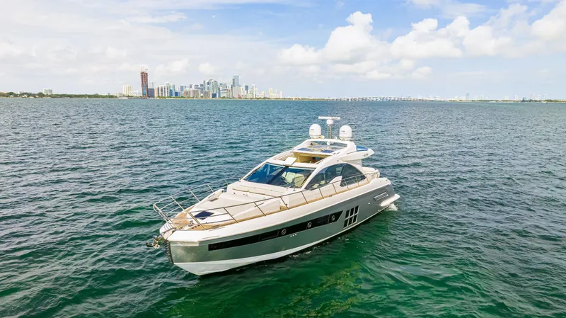 Slide: The Image of 2016 Azimut 55S yacht cruising on open water with city skyline in the background. - 18