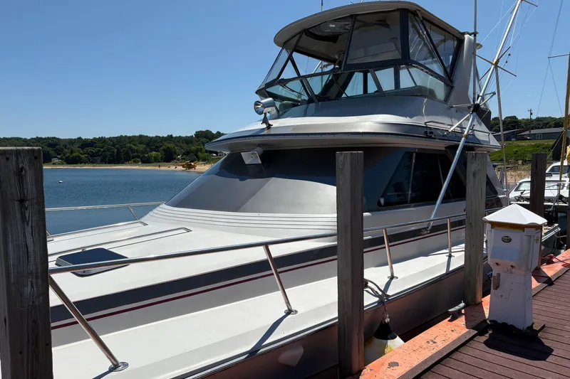 The Image of 1987 Sea Ray 460 Convertible docked at a marina on a sunny day. - 0