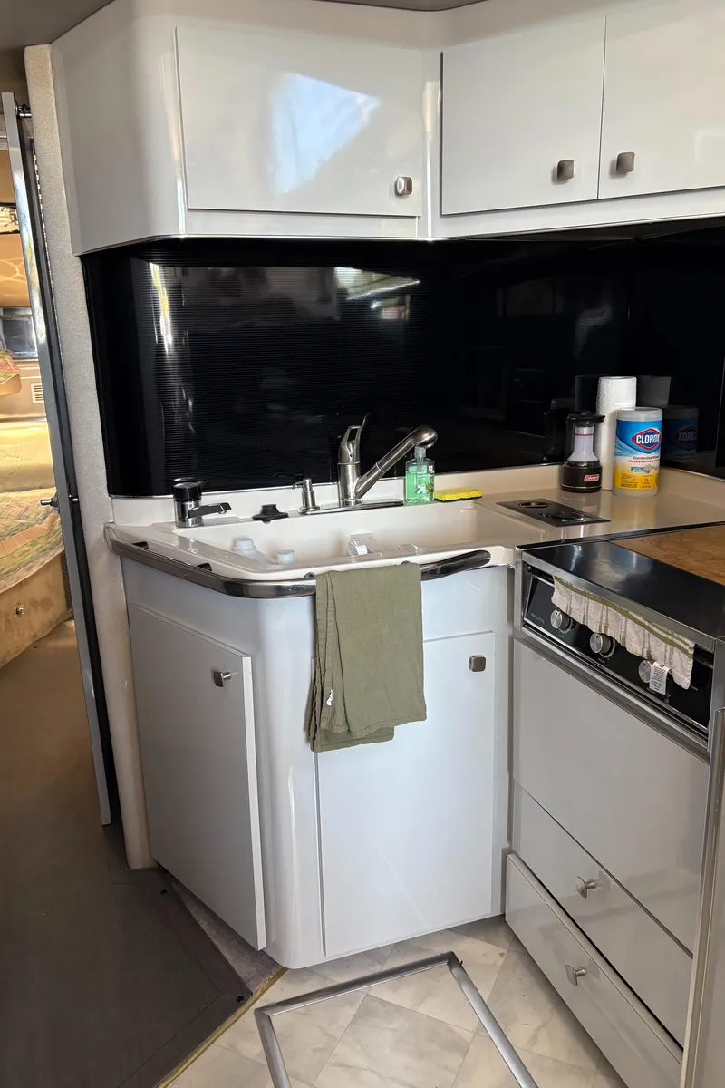 Slide: The Image of 1987 Sea Ray 460 Convertible yacht kitchen with sink, stove, and storage cabinets. - 14