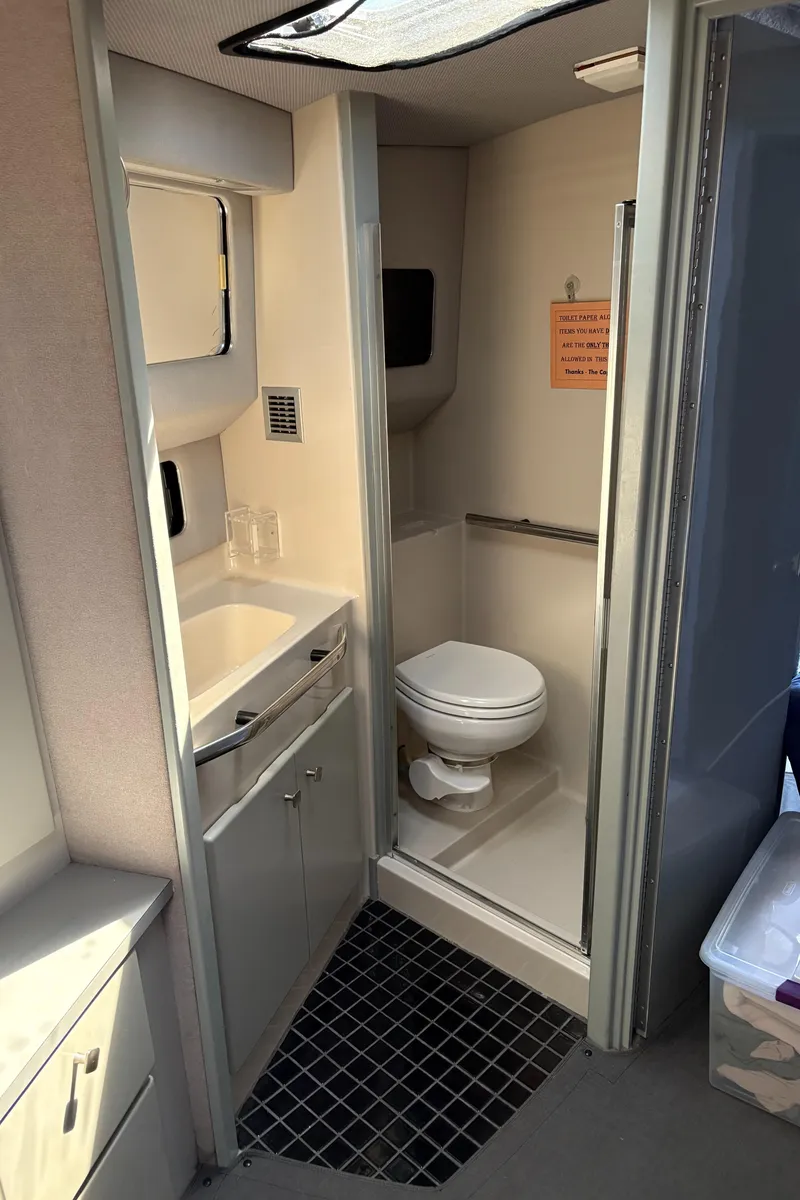 Slide: The Image of 1987 Sea Ray 460 Convertible yacht bathroom with sink, toilet, and storage cabinets. - 18