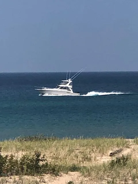Slide: The Image of 1987 Sea Ray 460 Convertible yacht cruising on open water near a sandy shoreline. - 24