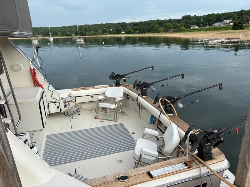 Slide: The Image of 1987 Sea Ray 460 Convertible boat with fishing rods, docked in a serene lake setting. - 3