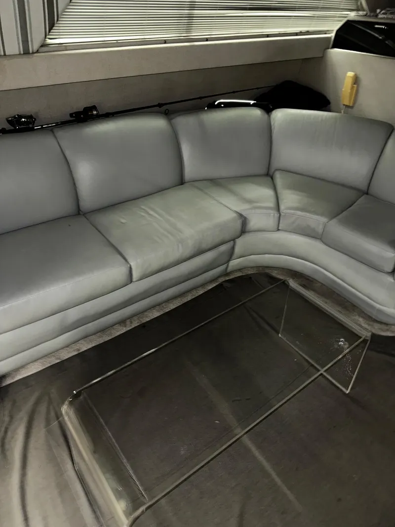 Slide: The Image of 1987 Sea Ray 460 Convertible interior with gray leather seating and glass coffee table. - 31