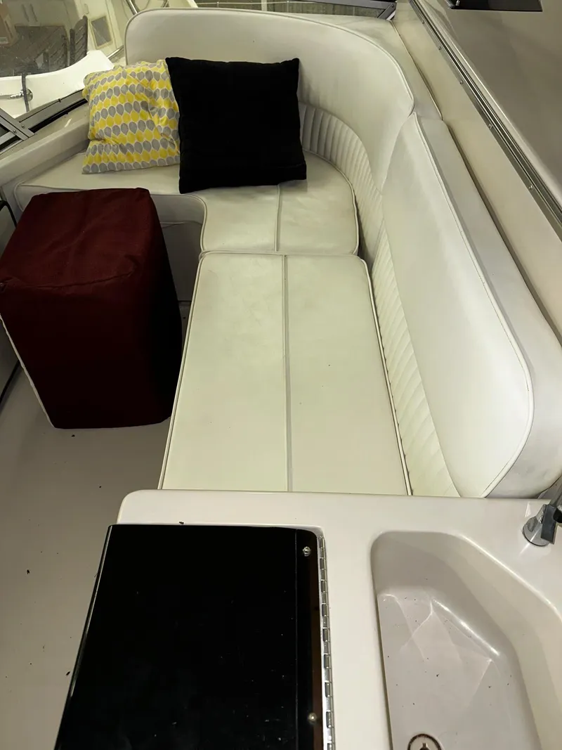 Slide: The Image of 1987 Sea Ray 460 Convertible interior with white seating, colorful cushions, and a compact sink area. - 44