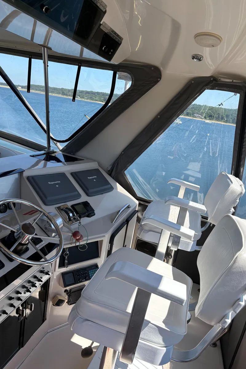 Slide: The Image of 1987 Sea Ray 460 Convertible yacht cockpit with steering wheel and white captain chairs. - 8